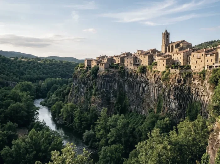 A village of stone houses on a clifftop above a wooded river gorge