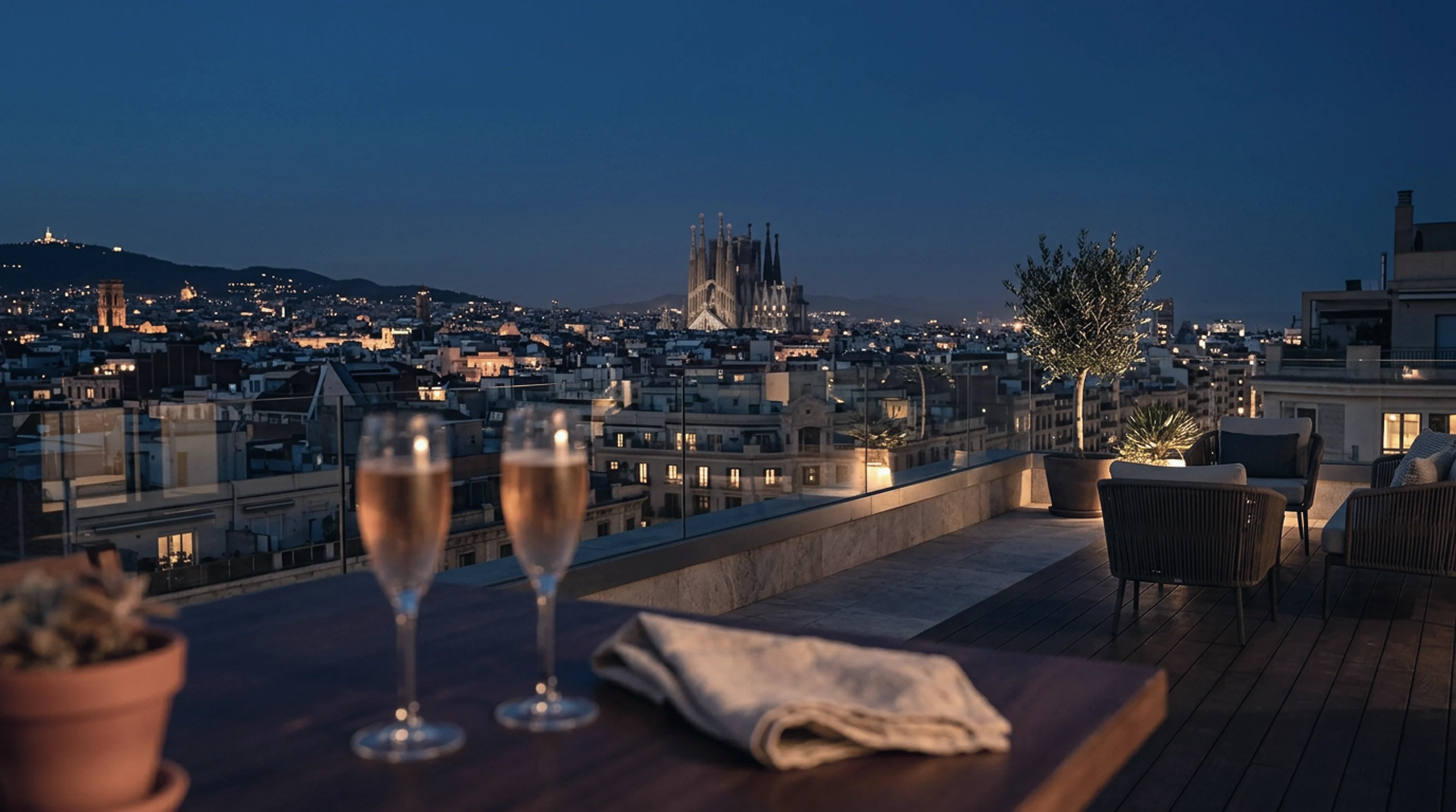 Two glasses of cava on a rooftop terrace with the Sagrada Família lit up at dusk