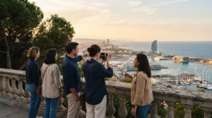 Small group with a guide at a stone balustrade on Montjuic, photographing Barcelona's port and marina in golden light